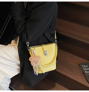 Détail du sac seau jaune à motif litchi avec pendentif ours et foulard en soie décoratif