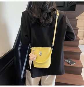Détail du sac seau en cuir jaune avec fermoir argenté et breloque ours en peluche