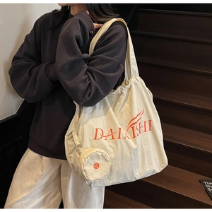Detail der Canvas-Einkaufstasche mit orangefarbenem Logo und kleinem rundem Reißverschlussetui