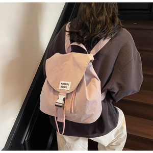 Detail of lavender canvas backpack featuring silver buckle, drawstring, and side zipper