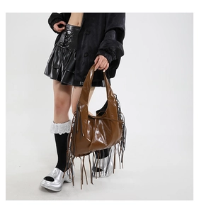 Close-up van de glanzende bruine PU-leren hobo-tas met lange franjes op een model