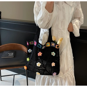 Dettaglio della borsa tote nera all'uncinetto con decorazioni floreali colorate in 3D
