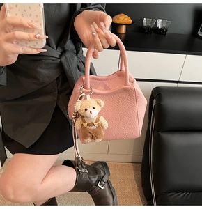 Primer plano del bolso saco de cuero rosa con un colgante de oso de peluche suave
