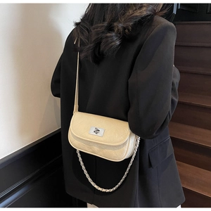 Detail view of cream quilted shoulder bag with silver turn-lock on black blazer outfit