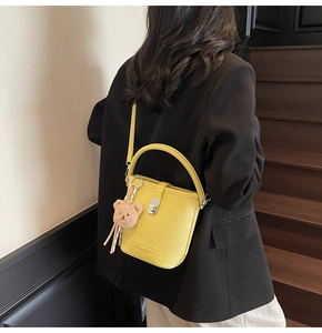 Détail du sac seau en cuir jaune vif avec fermoir argenté et breloque ours en peluche