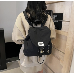 Detail of black canvas backpack showing metal buckle, woven label and durable nylon texture