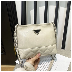 Close-up of cream leather bucket bag with quilted patterns and silver chain strap details