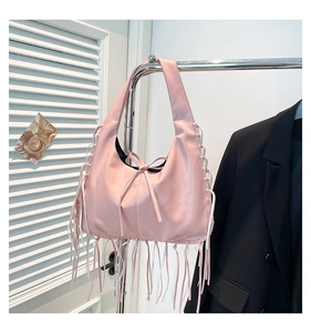 Macro view of the pink hobo bag showing fine leather fringe details and bow knot accent