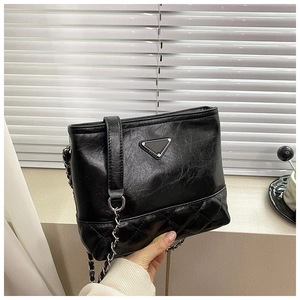 Detail of glossy wrinkled PU leather handbag with silver triangle logo and chain strap