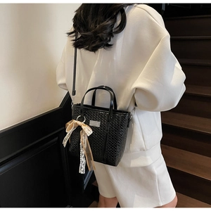 Detail of black woven bucket bag with lace ribbon and adjustable crossbody strap
