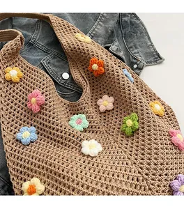 Close-up of handmade woven tote bag featuring colorful 3D crochet flower decorations