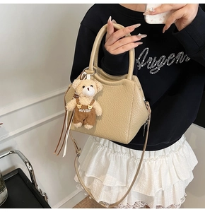 Detalle del bolso de cubo beige con textura de lichi y colgante de oso