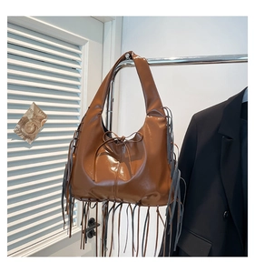 Detail view of a large brown faux leather tote bag with long stylish fringe and tie closure