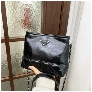 Close-up of black quilted shoulder bag with polished synthetic leather and silver chain