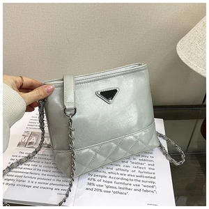 Detail of silver metallic quilted shoulder bag with chain strap and triangle logo plaque