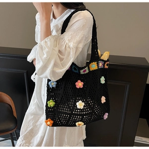 Dettaglio della borsa tote nera all'uncinetto con fiori 3D colorati tenuta da una modella