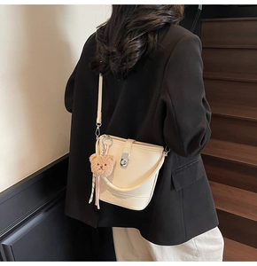 Détail du sac seau en cuir crème avec un petit ours en peluche marron sur le fermoir