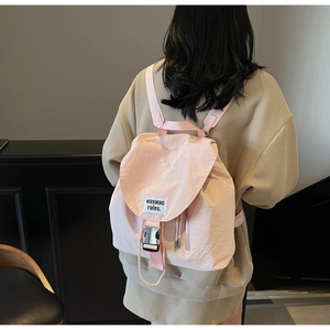 Detailed back view of model wearing a pink nylon backpack with flap and buckle closure