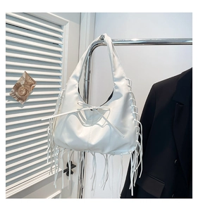 Close-up of white Hobo bag with long decorative fringes and bow detail on metal hanger