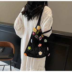Dettaglio della borsa tote in maglia nera con fiori all'uncinetto 3D e trama traforata