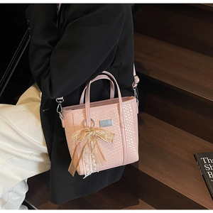 Borsa a secchiello rosa intrecciata con ciondolo a fiocco in pizzo e dettagli in metallo