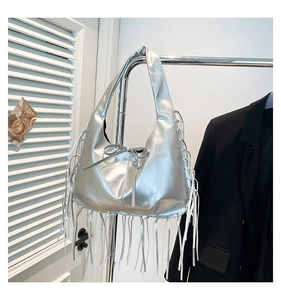 Detail of silver metallic tote bag with decorative bow and long hanging fringe tassels