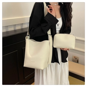Detailed view of cream bucket bag with litchi grain texture and matching small pouch