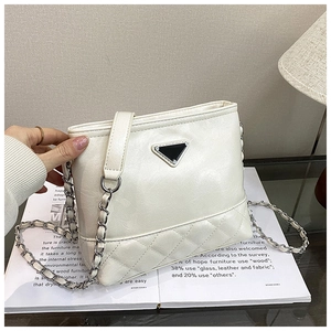 Detail of cream quilted bucket bag with chain strap and triangular metal plaque