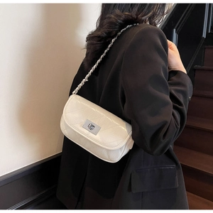 Chic white quilted mini crossbody bag with silver chain strap worn over a black blazer