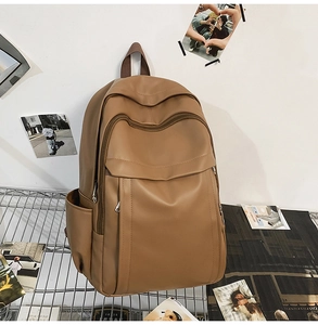 Detail of a brown leather backpack on a shelf showing spacious pockets and matte finish