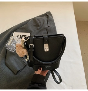 Détail du sac seau noir en cuir grainé avec fermoir argenté et petit pendentif d'ours