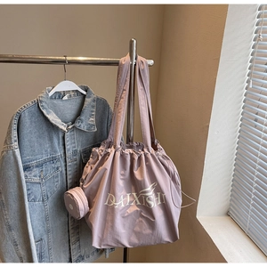 Detailansicht der lila Nylon-Tragetasche mit Kordelzug und angehängter Mini-Geldbörse