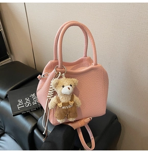 Detalle de bolso cubo de cuero litchi rosa con un lindo colgante de osito
