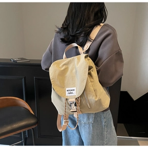 Detail of light khaki nylon backpack featuring buckle closure and fabric brand label