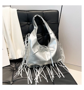 Detail of silver metallic tote bag with long fringe accents and a small bow detail