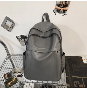 Close-up of grey matte backpack featuring multi-pocket zipper design and side pockets