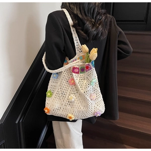 Dettaglio ravvicinato di una borsa tote in maglia bianca con fiori 3D colorati all'uncinetto