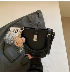 Détail du sac seau en cuir grainé noir avec fermoir rotatif argenté et bijou d'ours