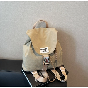Detail of light khaki nylon backpack with metal buckle closure and fabric brand label