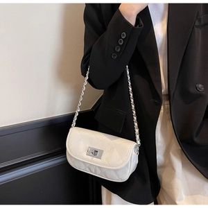 Detail of white quilted crossbody bag featuring silver metal twist lock and chain strap