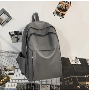 Detail of dark gray matte PU leather backpack front pocket on a metal display rack