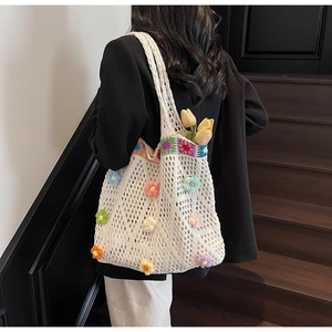Dettaglio della borsa tote all'uncinetto bianca con fiori 3D su sfondo blazer nero