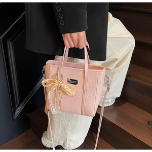 Detailed shot of pink woven texture handbag with lace bow and metal logo plaque