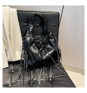 Detailed view of black patent leather tote bag with layered tassels and bow tie detail
