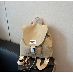 Detail of khaki nylon canvas backpack featuring drawstring closure and metal buckle