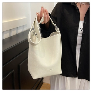 Detail of creamy white lychee grain leather bucket bag with wide shoulder strap