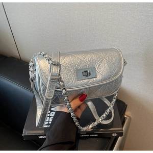 Detail of silver quilted chain bag with metallic texture and square twist lock closure