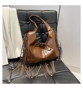 Close-up of the long fringe tassels and knotted bow detail on the brown PU leather hobo bag