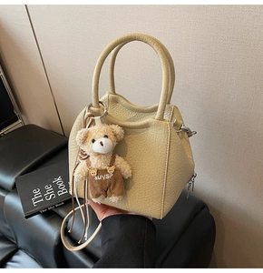 Detalle de bolso tipo cubo beige con textura de lichi y colgante de osito de peluche