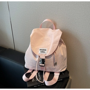 Detailed view of pink canvas backpack with buckle closure and brand label on fabric